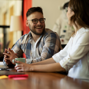 Manager and employee sitting at a table, smiling.